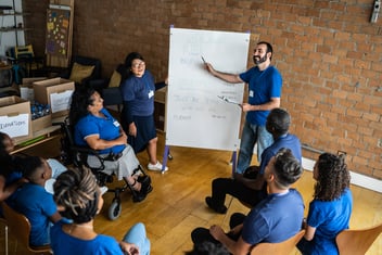 Man training a diverse group of volunteers in blue uniforms